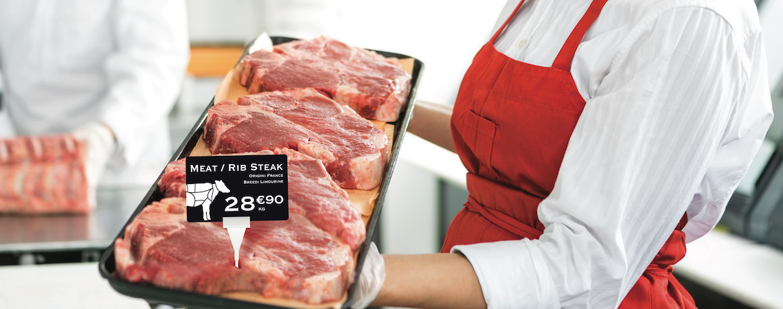 A butcher shop uses price cards that match products and branding